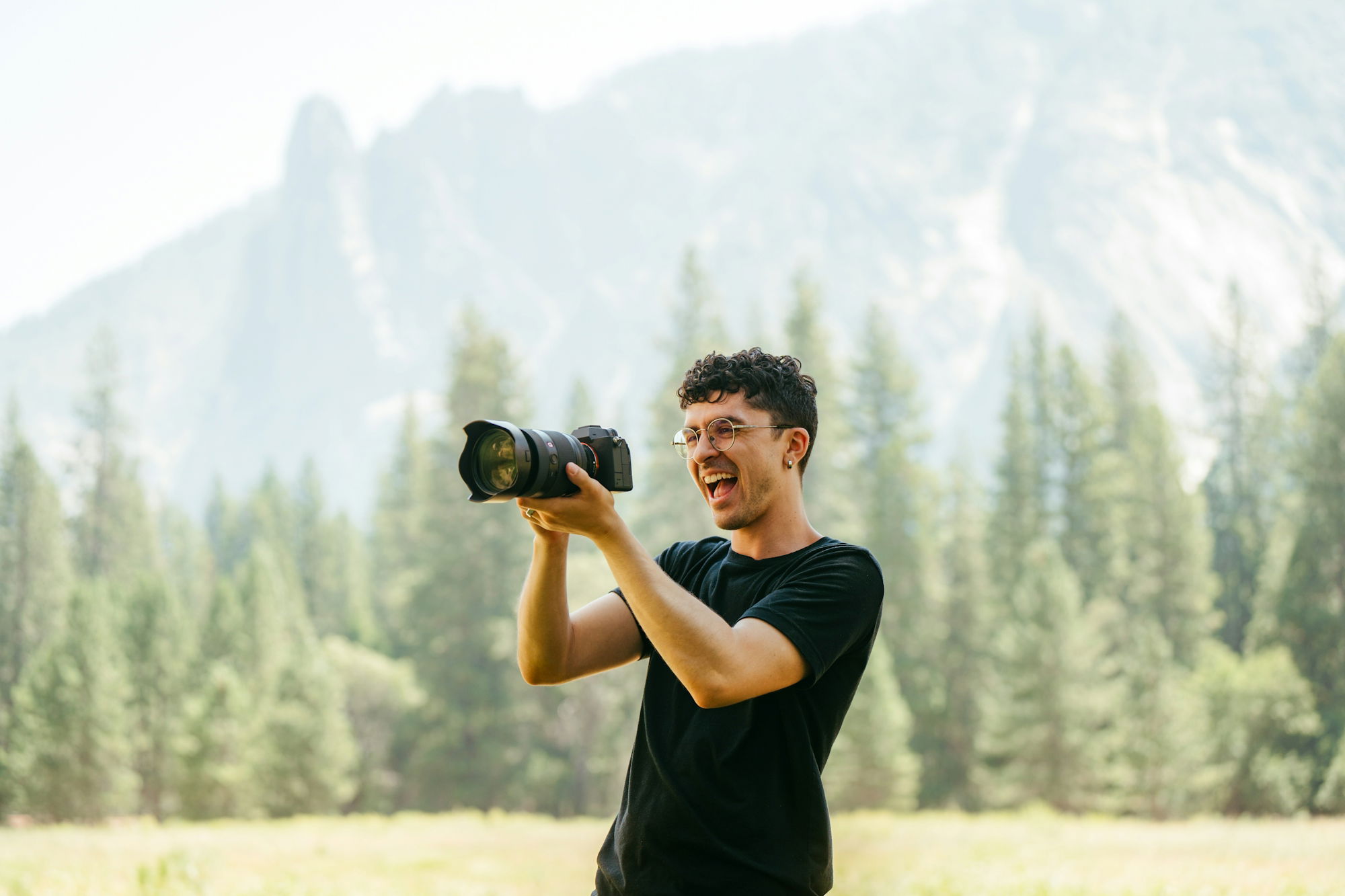 Man with camera taking picture in front of mountains